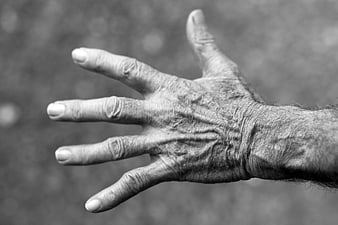 Close-up of wrinkled elderly hand in black and white