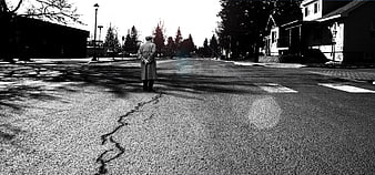 Lone man standing on cracked suburban street in black and white