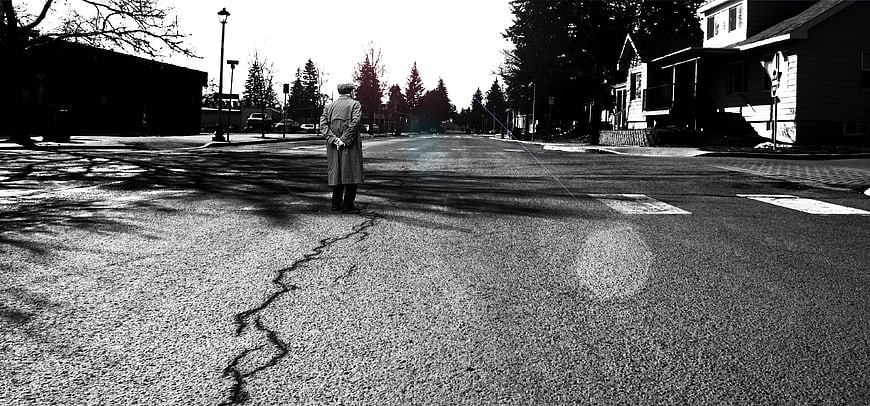Lone man standing on cracked suburban street in black and white