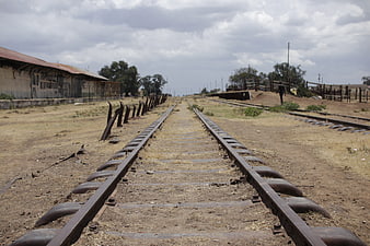 Rusty railway tracks leading to horizon in rural landscape