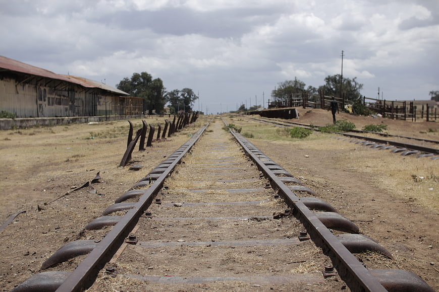Rusty railway tracks leading to horizon in rural landscape