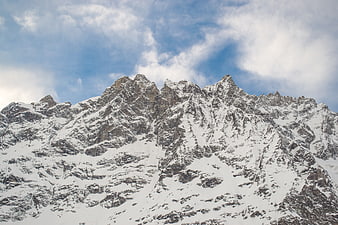Snow-covered mountain peaks against a blue sky with clouds