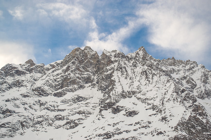 Snow-covered mountain peaks against a blue sky with clouds
