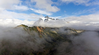 Majestic Snow-Capped Mountain Peak Rising Above Clouds