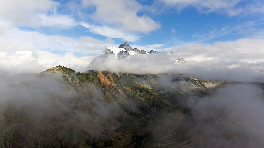 Majestic Snow-Capped Mountain Peak Rising Above Clouds