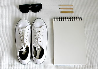 White sneakers, sunglasses, and notebook flat lay on textured background