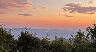 Scenic Sunset Over Layered Mountain Ranges with Trees