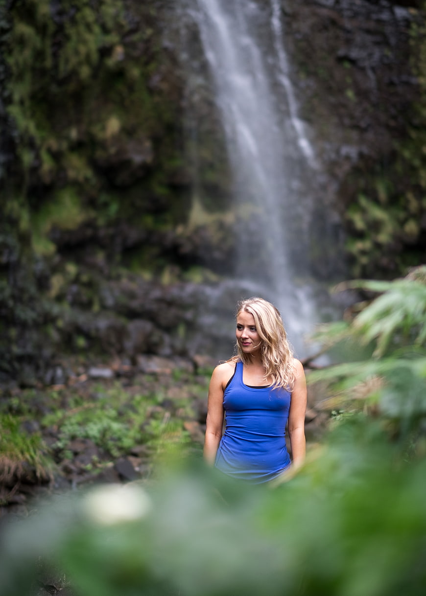 Blonde Woman in Blue Tank Top Standing by Waterfall