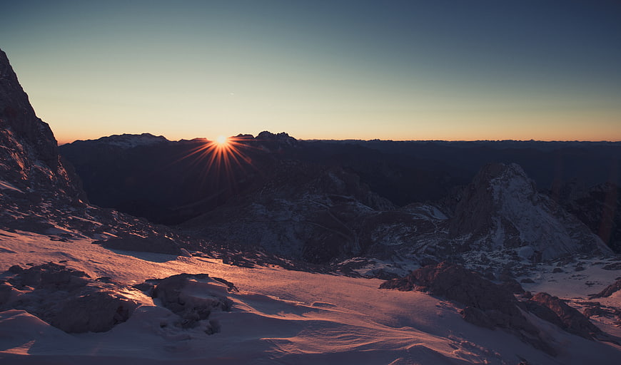 Sunset over Snowy Mountain Peaks with Starburst Effect