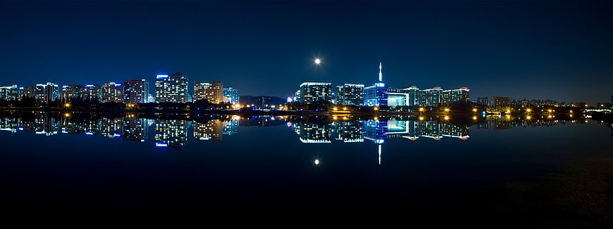 Panoramic night skyline of Seoul with moon and river reflections