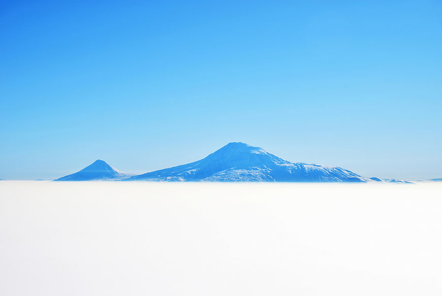 Snowy mountain peaks rising above a sea of clouds