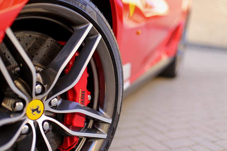 Close-up of Ferrari wheel with red brake caliper and yellow center cap