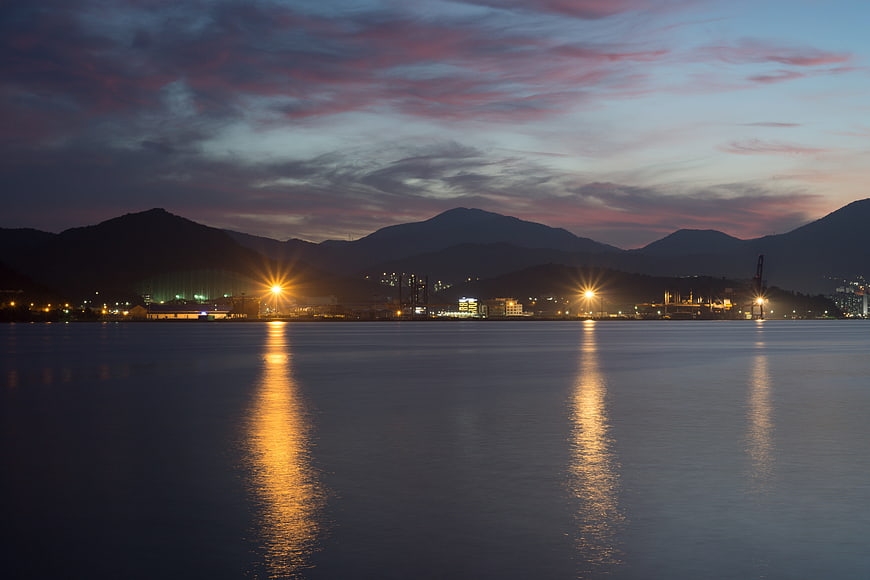 Dusk Landscape With Mountain Silhouettes And Water Reflections