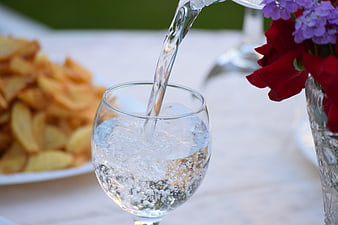 Pouring Sparkling Water Into Glass With Chips And Flowers