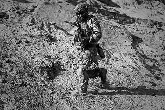 Soldier in full combat gear running through desert terrain