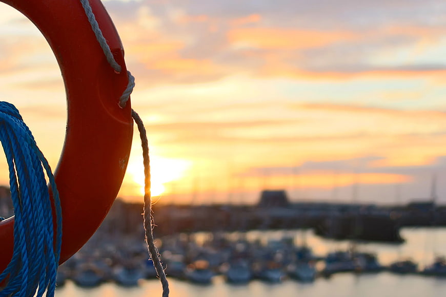 Red Lifebuoy and Blue Rope Against Sunset Marina