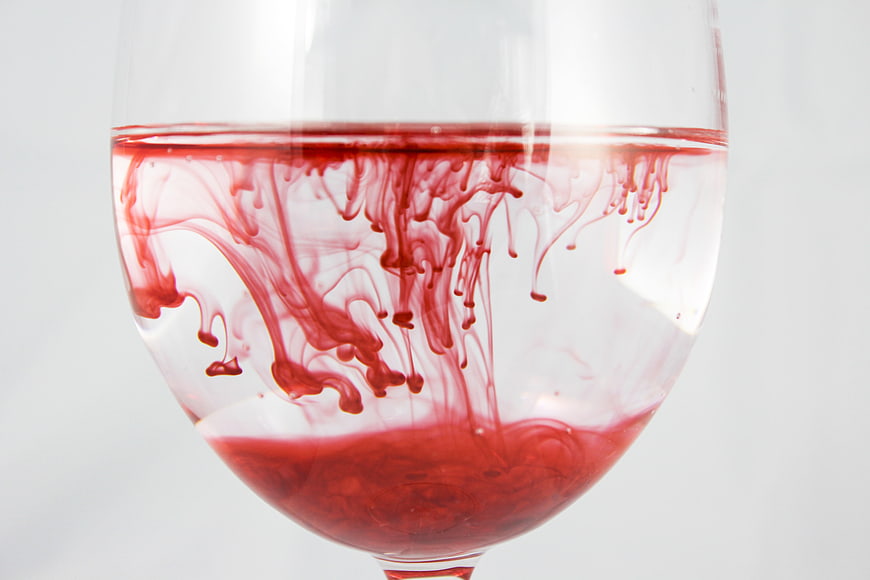 Red Ink Diffusing in Water Inside a Clear Glass