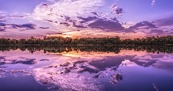 Vibrant Purple Sunset Reflection on a Calm Lake with Distant Trees