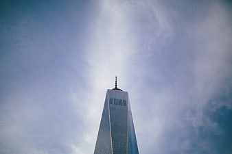 Low angle view of One World Trade Center skyscraper against cloudy sky