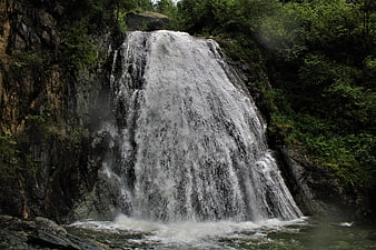 Powerful waterfall cascading down rocky cliff in lush forest