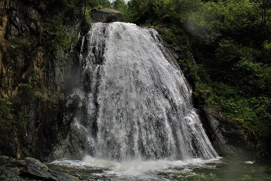 Powerful waterfall cascading down rocky cliff in lush forest