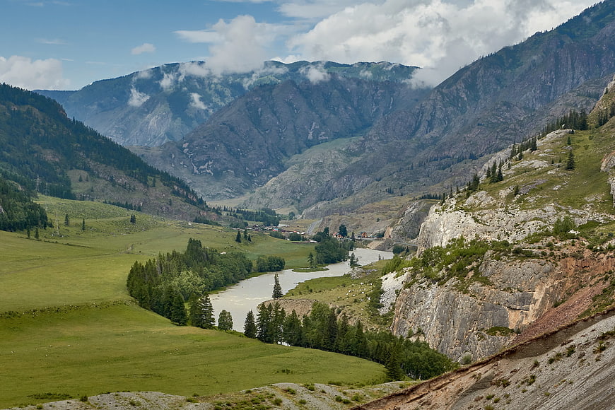 Panoramic mountain valley with winding river and green meadows