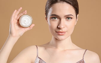 Woman holding skincare cream jar with healthy glowing skin