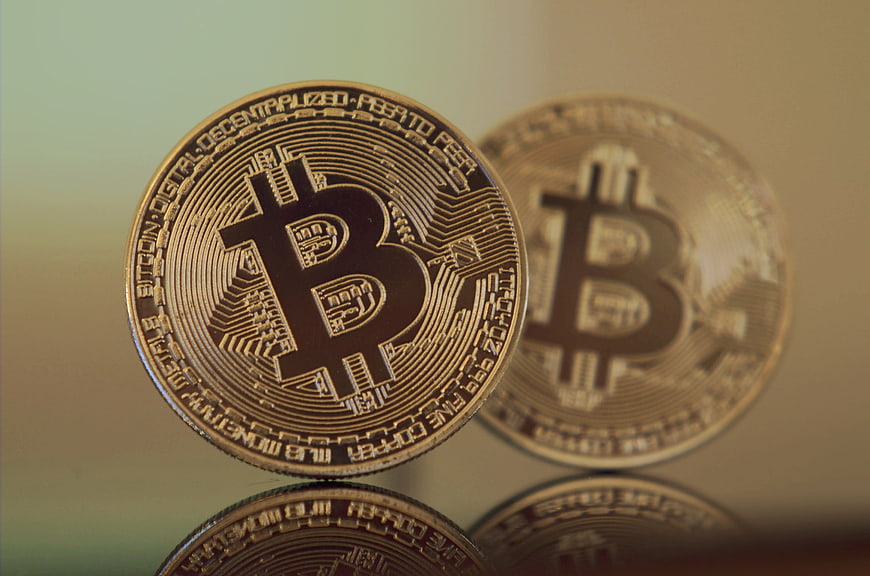 Close-up of physical gold Bitcoin coins on reflective surface