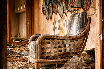 Dilapidated vintage armchair in abandoned room with graffiti