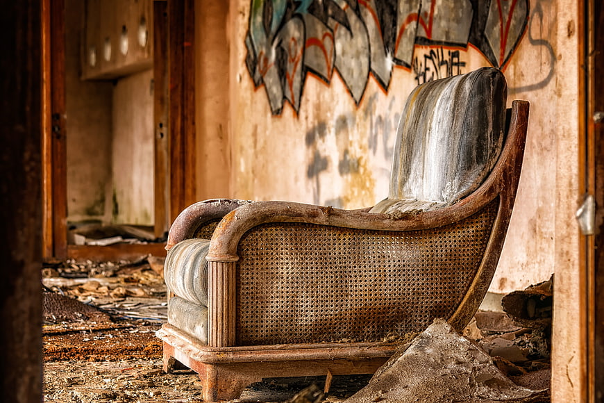 Dilapidated vintage armchair in abandoned room with graffiti