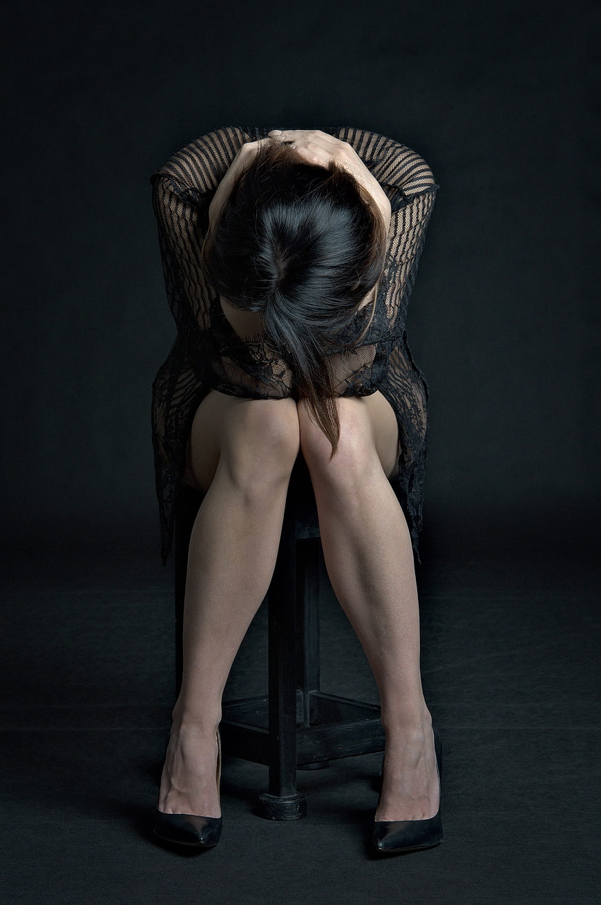 Emotional Portrait of Woman Sitting with Head in Hands