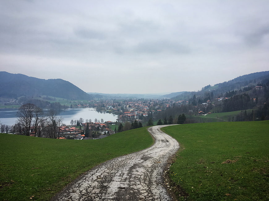 Winding gravel path through green hills overlooking a lakeside town