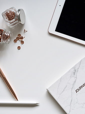 Minimalist white desk flat lay with tablet, journal, and rose gold stationery
