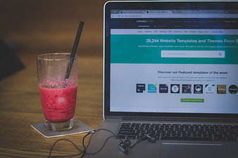 Laptop with website template screen and red smoothie drink