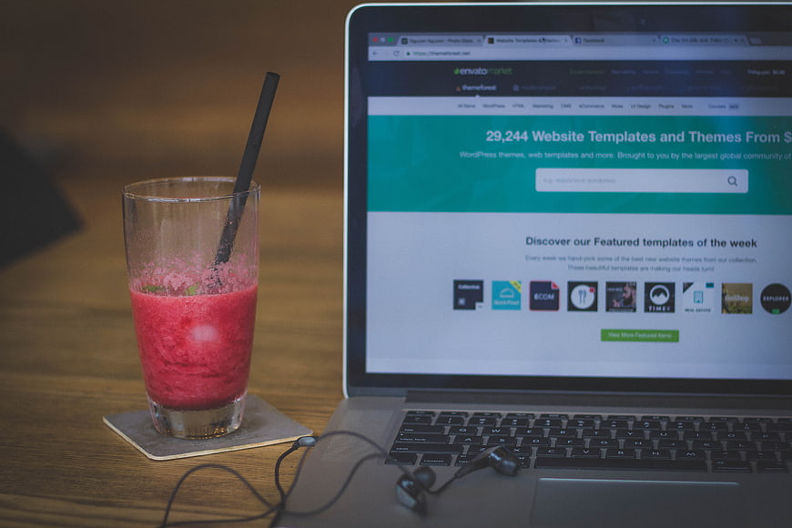 Laptop with website template screen and red smoothie drink