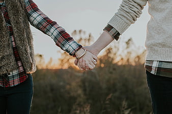 Couple Holding Hands in Plaid Shirts at Sunset