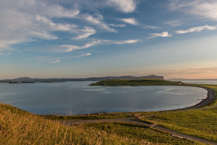 Scenic coastal landscape with grassy hills and calm water