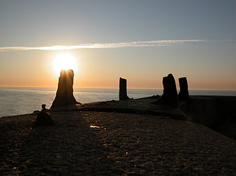 Silhouetted rock formations on a beach at sunset