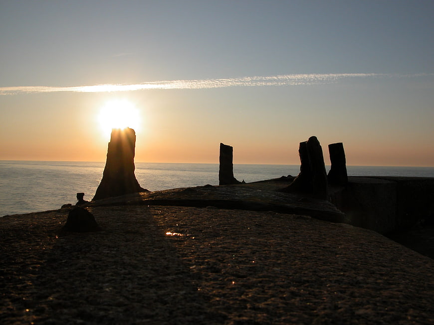 Silhouetted rock formations on a beach at sunset