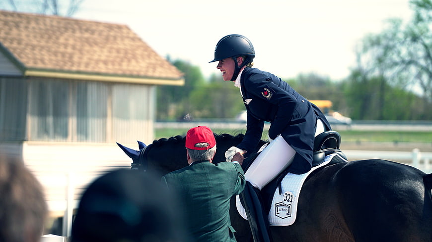 Equestrian Rider Smiling While Being Assisted on Horse