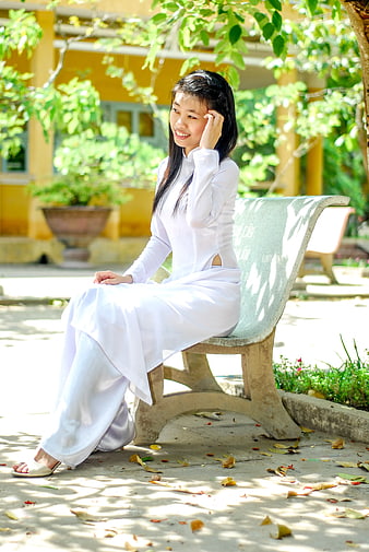 Young Vietnamese Woman in White Ao Dai Sitting on Bench