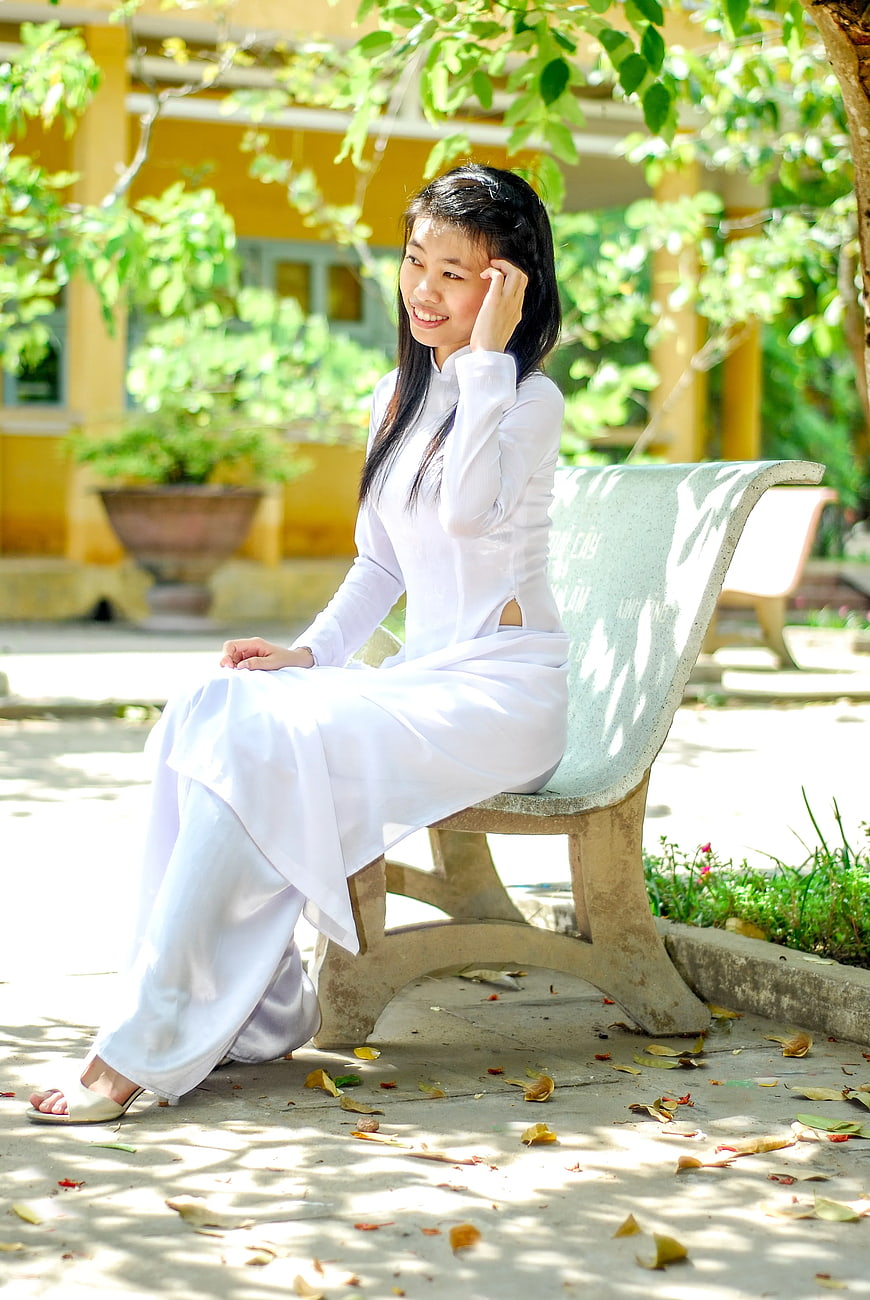 Young Vietnamese Woman in White Ao Dai Sitting on Bench