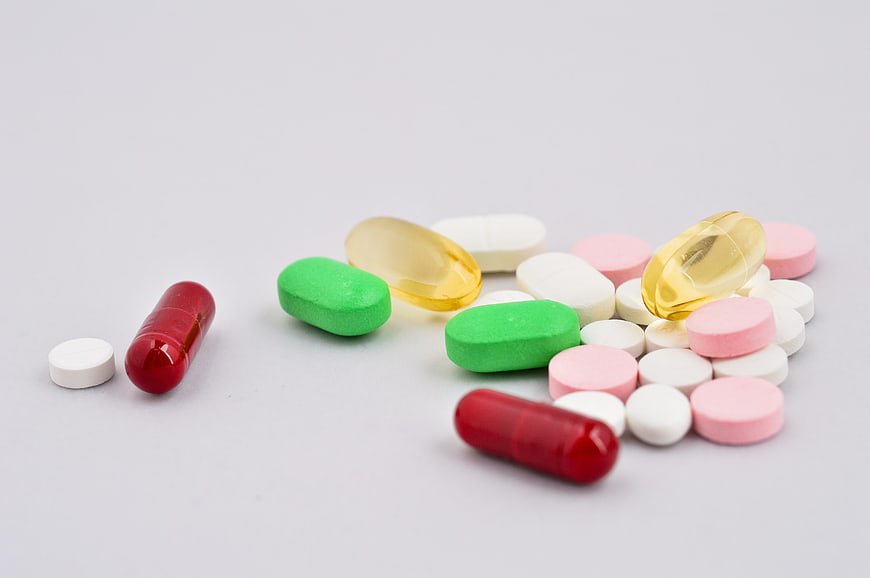 Assorted colorful pills and capsules on white background