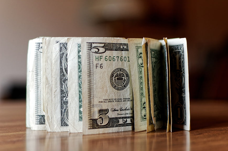 US Dollar Bills Arranged Like Books on Wooden Table
