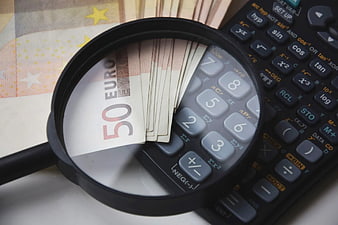 Magnifying glass over 50 Euro banknotes and calculator