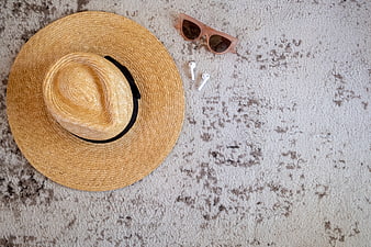 Summer vacation flat lay with straw hat, sunglasses, and earbuds