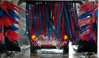 Red car being washed in automatic car wash tunnel