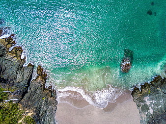 Aerial View of Turquoise Ocean Waves Crashing on Rocky Beach