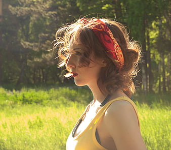 Redhead woman in yellow tank top and red headband in sunny summer field
