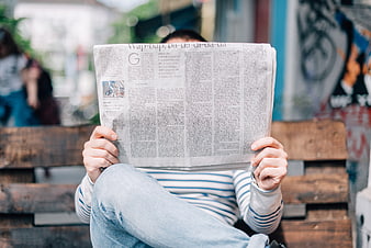 Man Reading Newspaper on Wooden Bench Outdoors